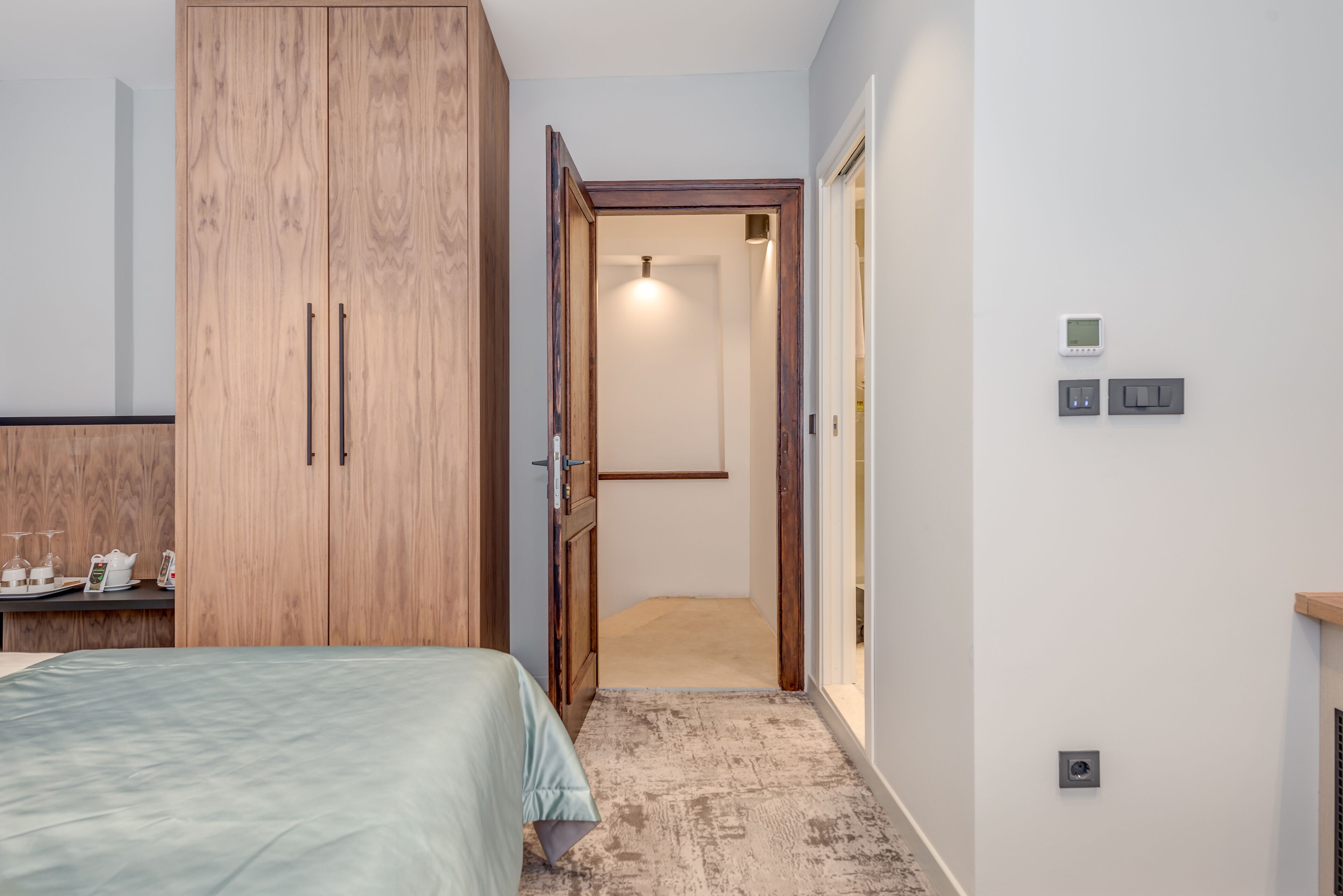 Une chambre à coucher avec un lit, une armoire en bois et une petite table sur laquelle se trouvent une bouilloire et des tasses.