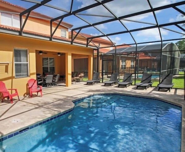 A covered outdoor swimming pool with lounge chairs and a patio area.