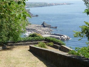 A coastal view with a stone pathway leading to a rocky area by the sea.