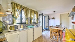 A compact kitchen with a microwave, sink, and dining area with chairs. - Casa Guardia Bilocal Apartment Near the sea (Acireale)