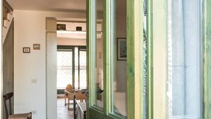 A hallway with a wooden door, a chair, a table, and a window with a view. - Casa Guardia Bilocal Apartment Near the sea (Acireale)