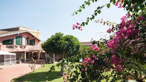 A house with a garden, a tree, and pink flowers. - Casa Guardia Bilocal Apartment Near the sea (Acireale)