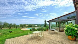 Un patio con tavolo e sedie, una piscina e vista sulla campagna.