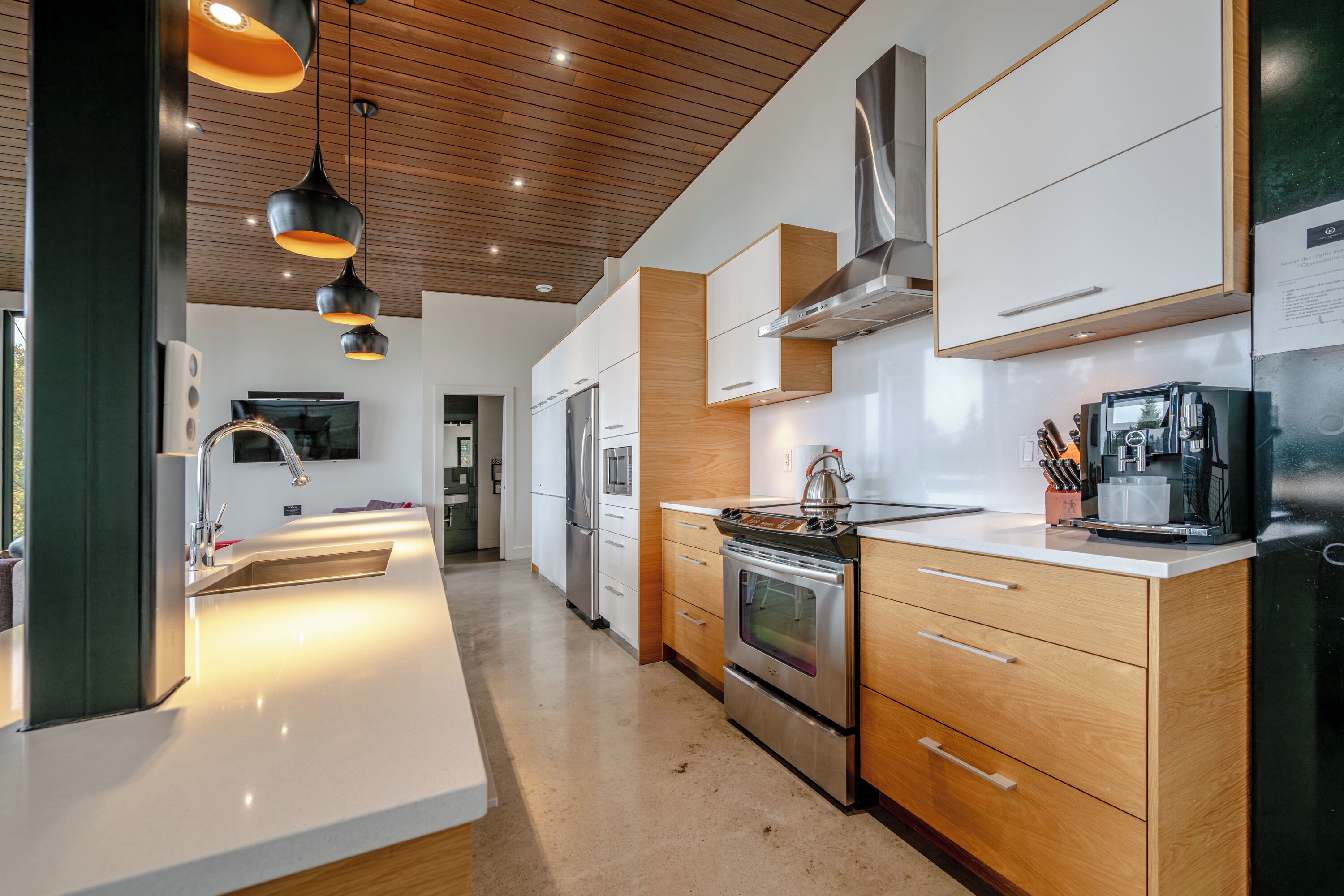 A modern kitchen with wooden cabinets, stainless steel appliances, and pendant lighting.