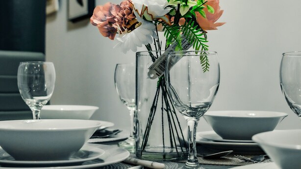 A dining table set with plates, bowls, cutlery, and a vase with flowers. - Bv Cosy Basement Apartment At Conditioning House (Bradford)