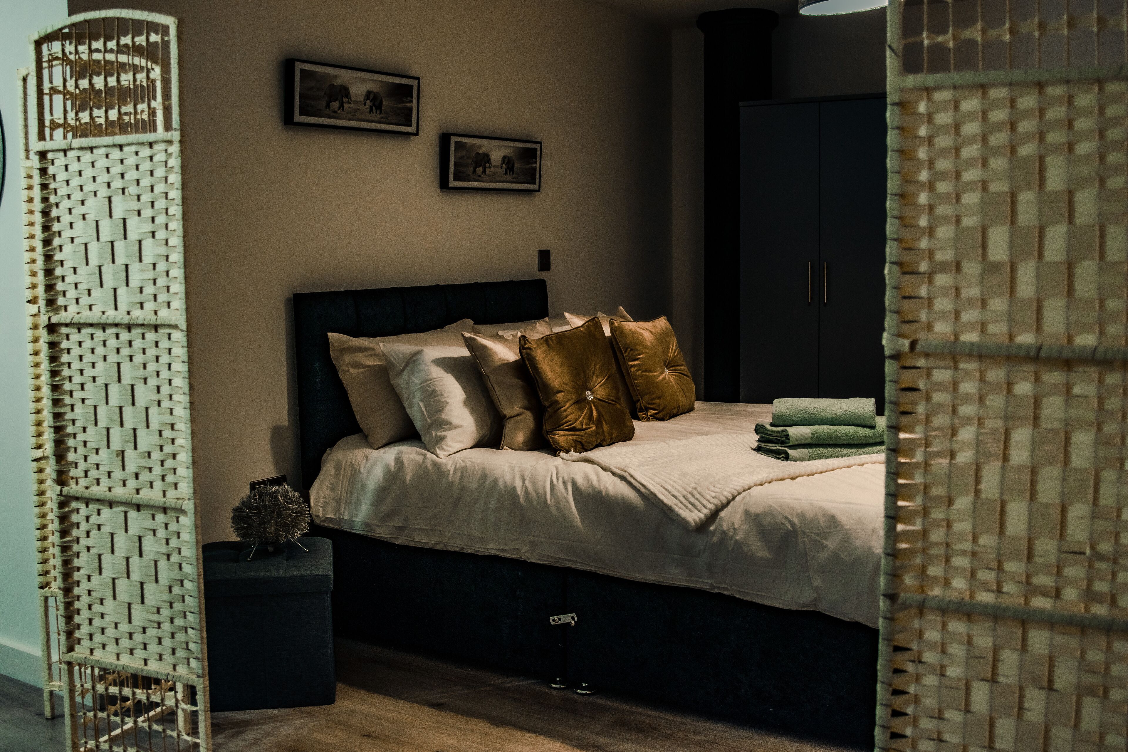A bedroom with a bed, pillows, a bedside table, and a wardrobe.