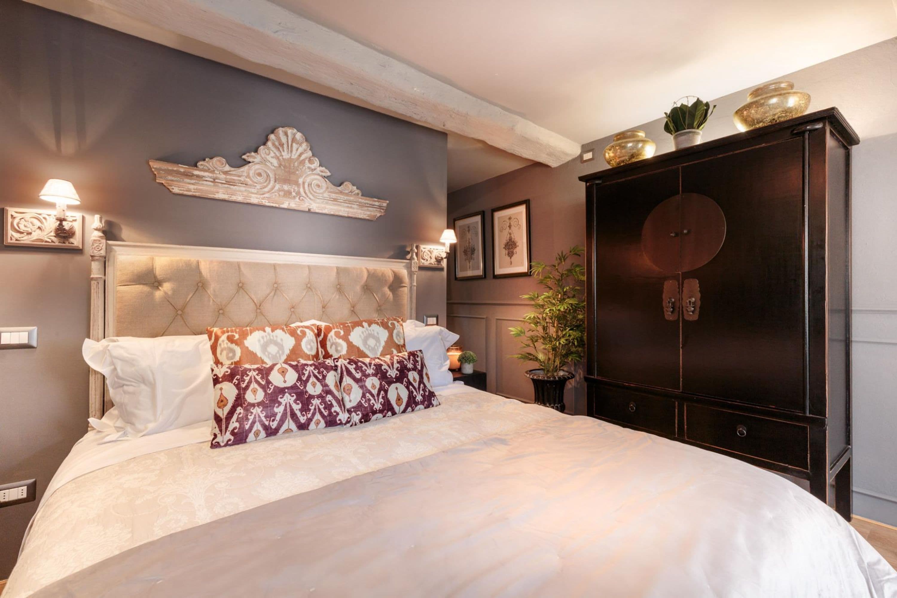 Een slaapkamer met een groot bed, een donker houten kledingkast en een decoratief wandobject.