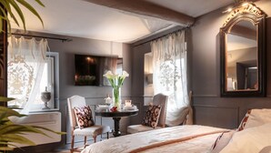 A bedroom with a large bed, two chairs, a small table with a vase of flowers, and a large mirror on the wall. - Casa Palatial in Lucca (Lucca)