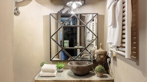 A bathroom with a stone sink, a mirror with a geometric frame, and a towel rack. - Casa Palatial in Lucca (Lucca)