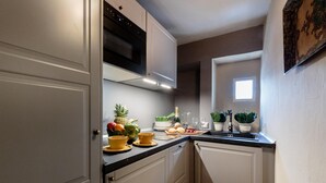 A compact kitchen with white cabinets, a black microwave, and a small window. - Casa Palatial in Lucca (Lucca)