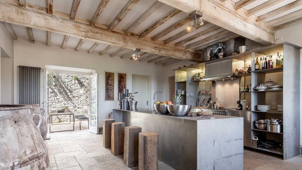 A modern kitchen with a central island, wooden stools, and a stone-tiled floor. - Palazzo Giusti in Pescaglia (Pescaglia)