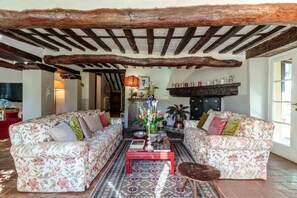 A cozy living room with two floral-patterned sofas, a red coffee table, and a patterned rug.
