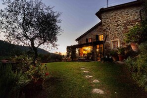 A stone house with a covered patio, a lawn, and potted plants. - Casa Nel Bosco in Santa Maria del Giudice (Lucca)