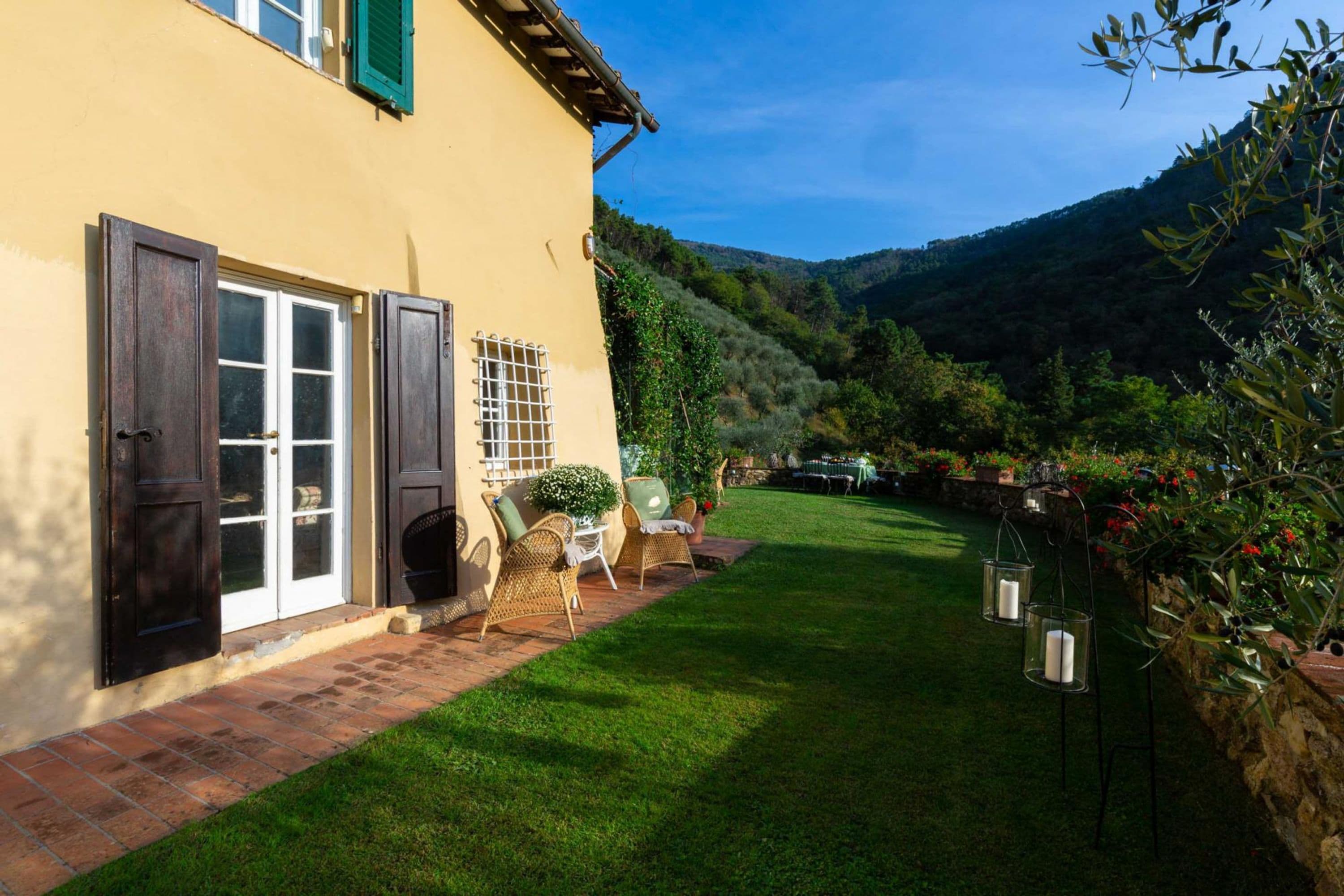 A house with a paved patio, outdoor furniture, and a well-maintained lawn.