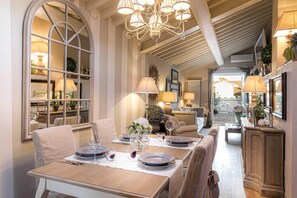 A dining area with a long table set for a meal, a chandelier, and a view of the outside. - Casa Laura a Terrace Above Lucca (Lucca)