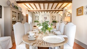 A dining room with a wooden table set for six, surrounded by white upholstered chairs. - Villa Alberta in Lucca (Lucca)