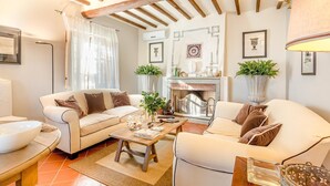 A cozy living room with two sofas, a fireplace, and a dining area with a table and chairs. - Villa Alberta in Lucca (Lucca)