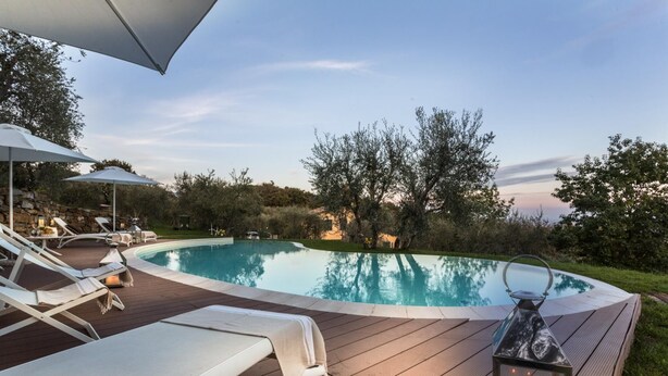 A pool area with lounge chairs and a wooden deck. - Villa Alberta in Lucca (Lucca)