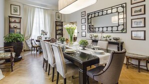 A dining room with a long table set for six, surrounded by chairs. There is a large mirror on the wall, and various framed pictures and a bookshelf. - Casa Barbra in Lucca (Lucca)