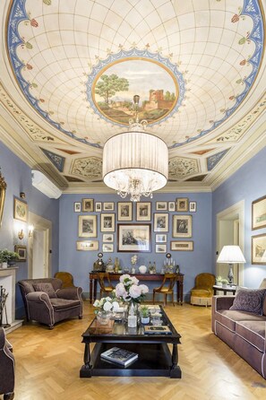 Um quarto com um candelabro, quadros nas paredes e uma mesa de centro com flores.