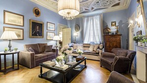 A spacious living room with a chandelier, sofas, a coffee table, and framed artwork on the walls. - Casa Barbra in Lucca (Lucca)