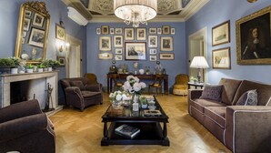 A room with a fireplace, a chandelier, framed pictures on the wall, and a sofa. - Casa Barbra in Lucca (Lucca)