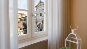 A room with a window overlooking a historic building, a white lantern, and a potted plant. - Casa Cachi 2 in Lucca (Lucca)
