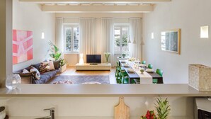 A modern living room with a sofa, TV, dining table, and chairs. - Casa Cachi 2 in Lucca (Lucca)