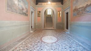 A hallway with a marble floor, a central staircase, and decorative wall paintings. - Casa Daniela in Lucca (Lucca)