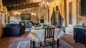 A rustic dining area with a stone wall, wooden ceiling beams, and a chandelier. - La Dimora dei Conti in Capannori (Capannori)