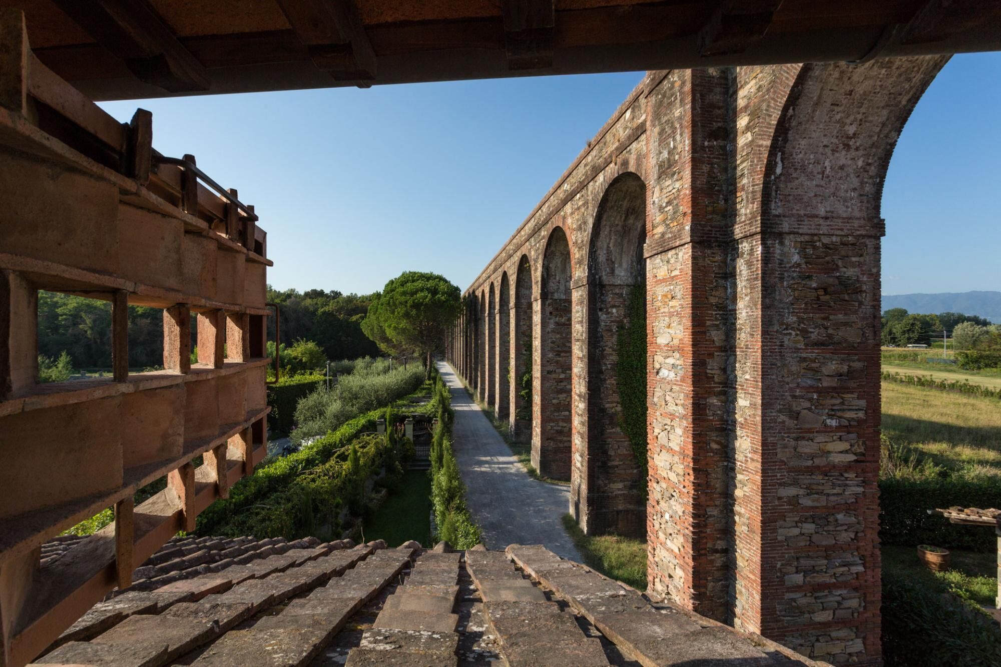 Un puente de piedra con arcos, un sendero y vistas al campo.