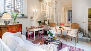 Amplia sala de estar con mesa de comedor, varias sillas, un sofá y una escalera.