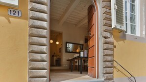 A doorway leading into a room with a wooden table and chairs, a mirror, and a window with shutters. - Casa Janca in Lucca With 1 Bedrooms and 2 Bathrooms (Lucca)
