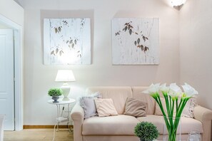 A living room with a beige sofa, a small side table with a lamp, and two wall-mounted paintings. - Casa Giustina in Lucca (Lucca)