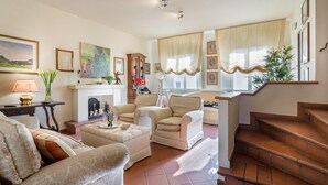 A spacious living room with a fireplace, comfortable seating, and a staircase leading to an upper level. - Casa Emy in Lucca With 3 Bedrooms and 2 Bathrooms (Lucca)