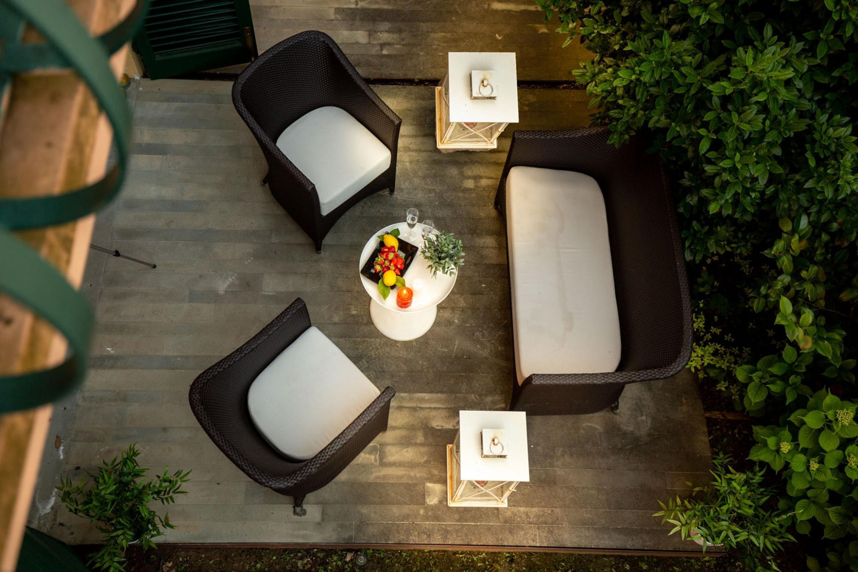 Un espace extérieur aménagé avec des meubles en osier et une petite table sur laquelle sont disposés un panier de fruits et des fleurs.