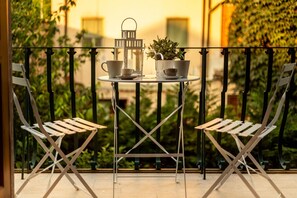 A balcony with two folding chairs, a small round table, a lantern, and a potted plant. - Casa Patricia in Lucca (Lucca)