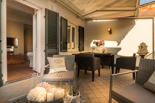 An outdoor patio area with wicker furniture, a dining table, and a staircase. - Casa Raffa in Lucca With 2 Bedrooms and 2 Bathrooms (Lucca)