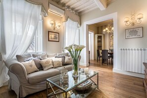 A cozy living room with a beige sofa, glass coffee table, and a vase of white flowers. - Casa Raffa in Lucca With 2 Bedrooms and 2 Bathrooms (Lucca)