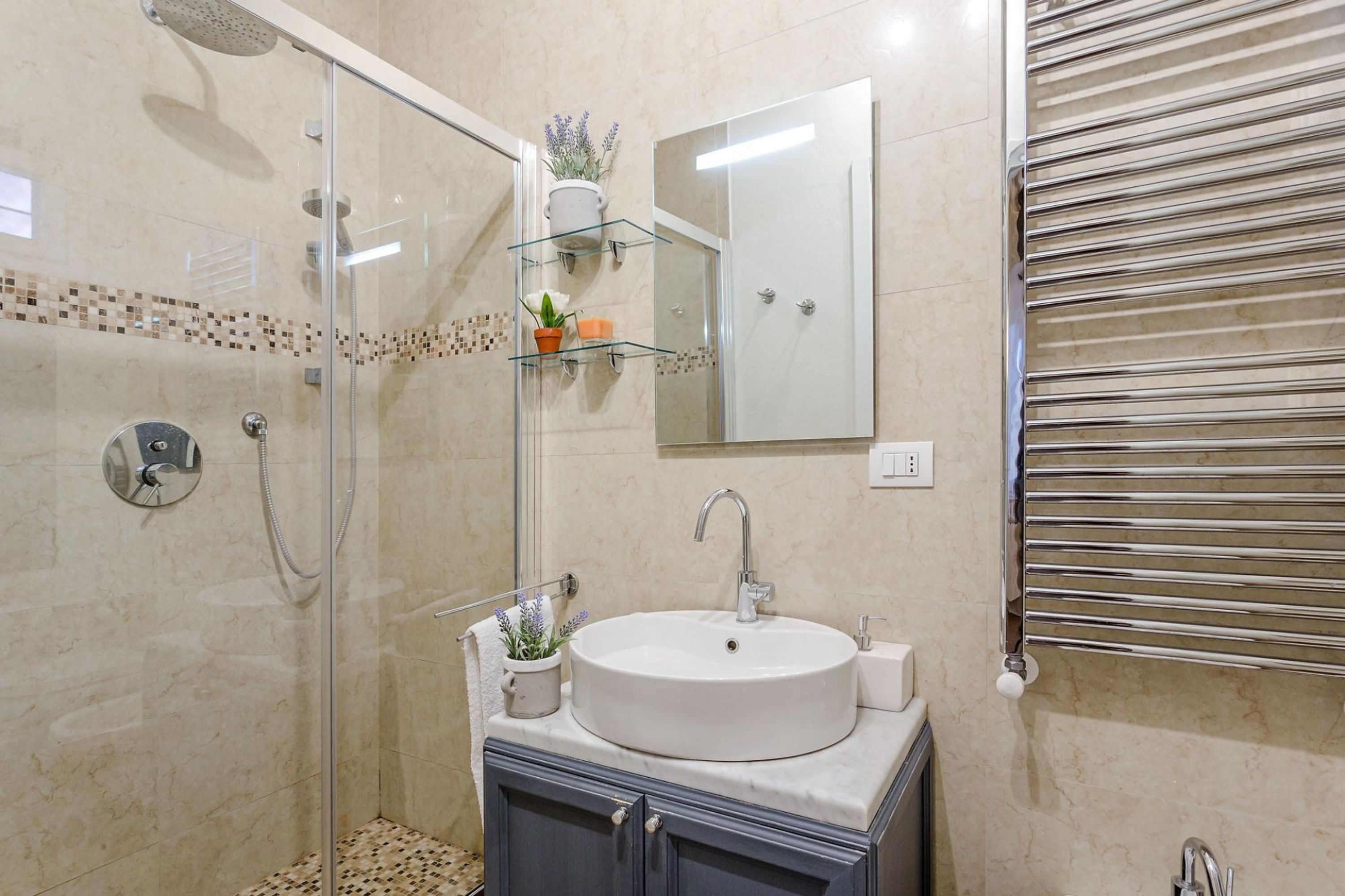 A modern bathroom with a glass-enclosed shower, a white sink, and a mirror above it.