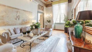 Una habitació àmplia amb un quadre gran, un sofà blanc, una taula de cafè i un vas verd.