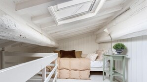 Ein Schlafzimmer im Loft-Stil mit Etagenbett, Glasdach, Nachttisch mit Pflanze und kleinem Fenster.