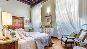 A bedroom with a bed, a nightstand, a dresser, a chair, and a mirror. - Casa Simonetta in Lucca (Lucca)
