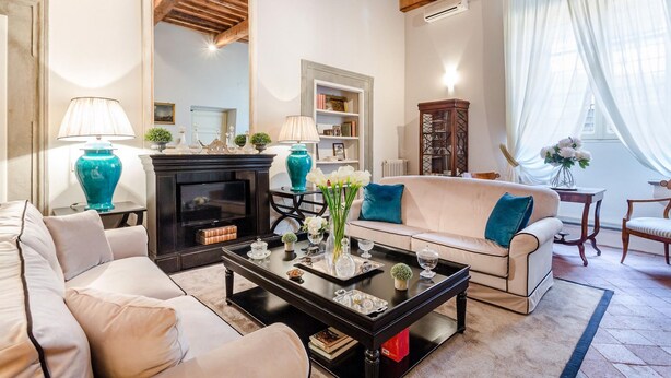 A living room with a fireplace, a sofa, a coffee table, and a bookshelf. - Casa Simonetta in Lucca (Lucca)