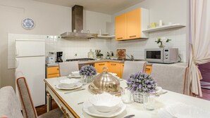 A modern kitchen with white cabinets, a microwave, and a dining area set with white plates and flowers. - Casa Simonetta in Lucca (Lucca)