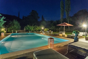 A rectangular swimming pool with a tiled deck, surrounded by lounge chairs and a covered seating area. - Bicocche Stone Farmhouse (Camaiore)