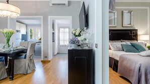A modern living room with a dining area, a black entertainment unit, and a bedroom with a bed and nightstand. - Ottone Penthouse in Lucca (Lucca)