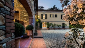 A courtyard with a stone wall, a tiled pathway, and potted plants. - Villa Clara in Capannori (Capannori)
