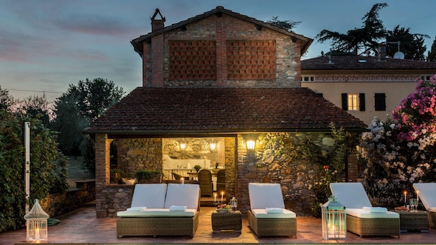 A poolside area with lounge chairs and a stone building with a tiled roof. - Villa Clara in Capannori (Capannori)
