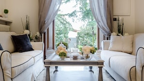 A room with a sofa, a coffee table, and a window with curtains. - Villa Clara in Capannori (Capannori)
